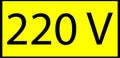 Yellow sign with a black border and the inscription 220 v